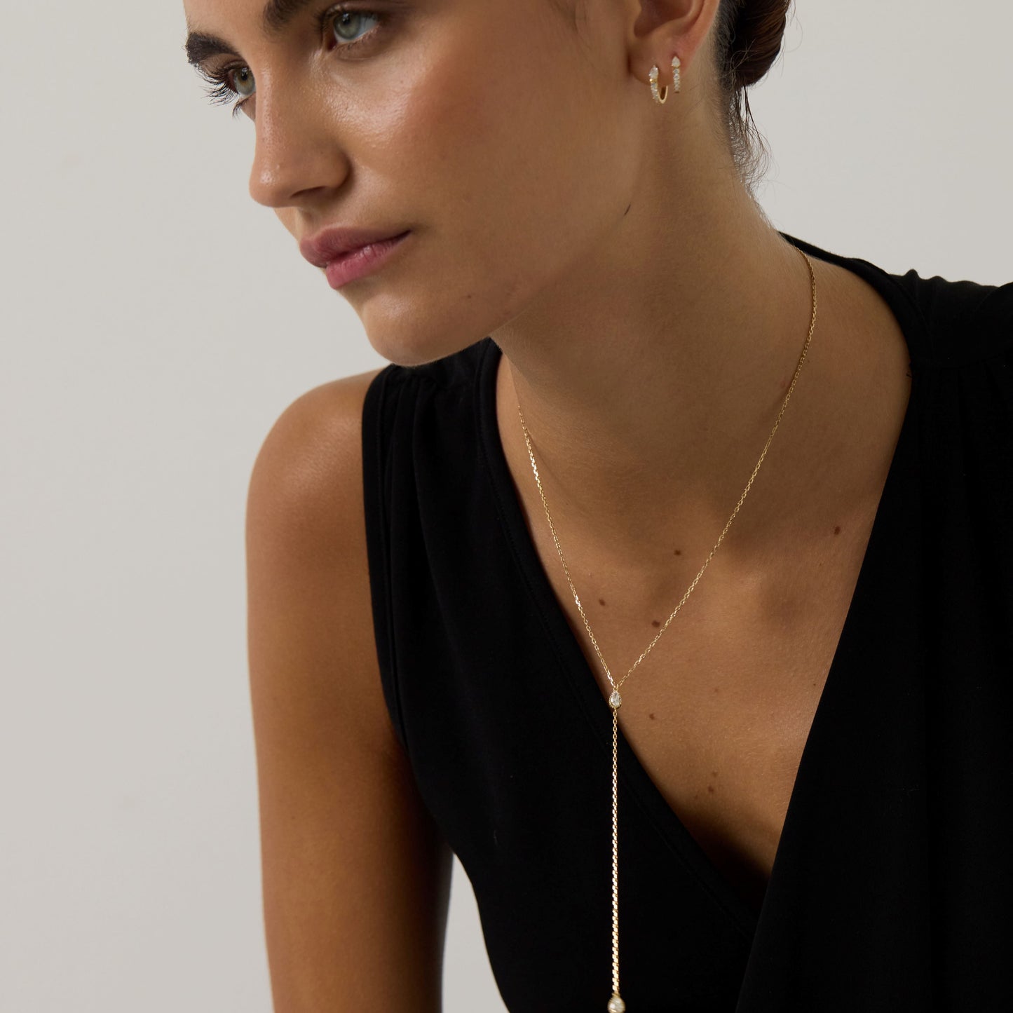 Woman wearing a delicate necklace with a minimalistic background