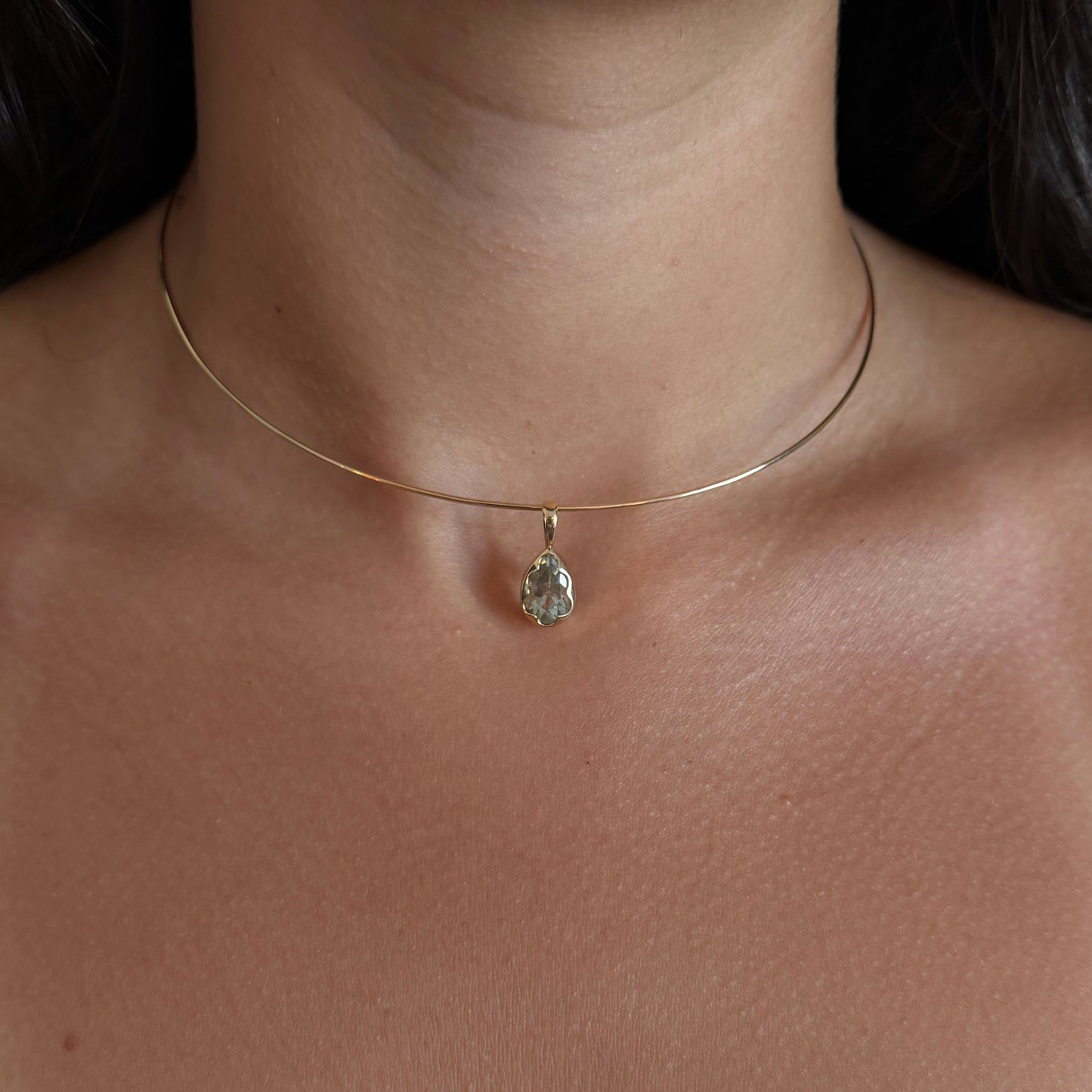 Close-up of a delicate necklace with a small pendant on a person's neck.