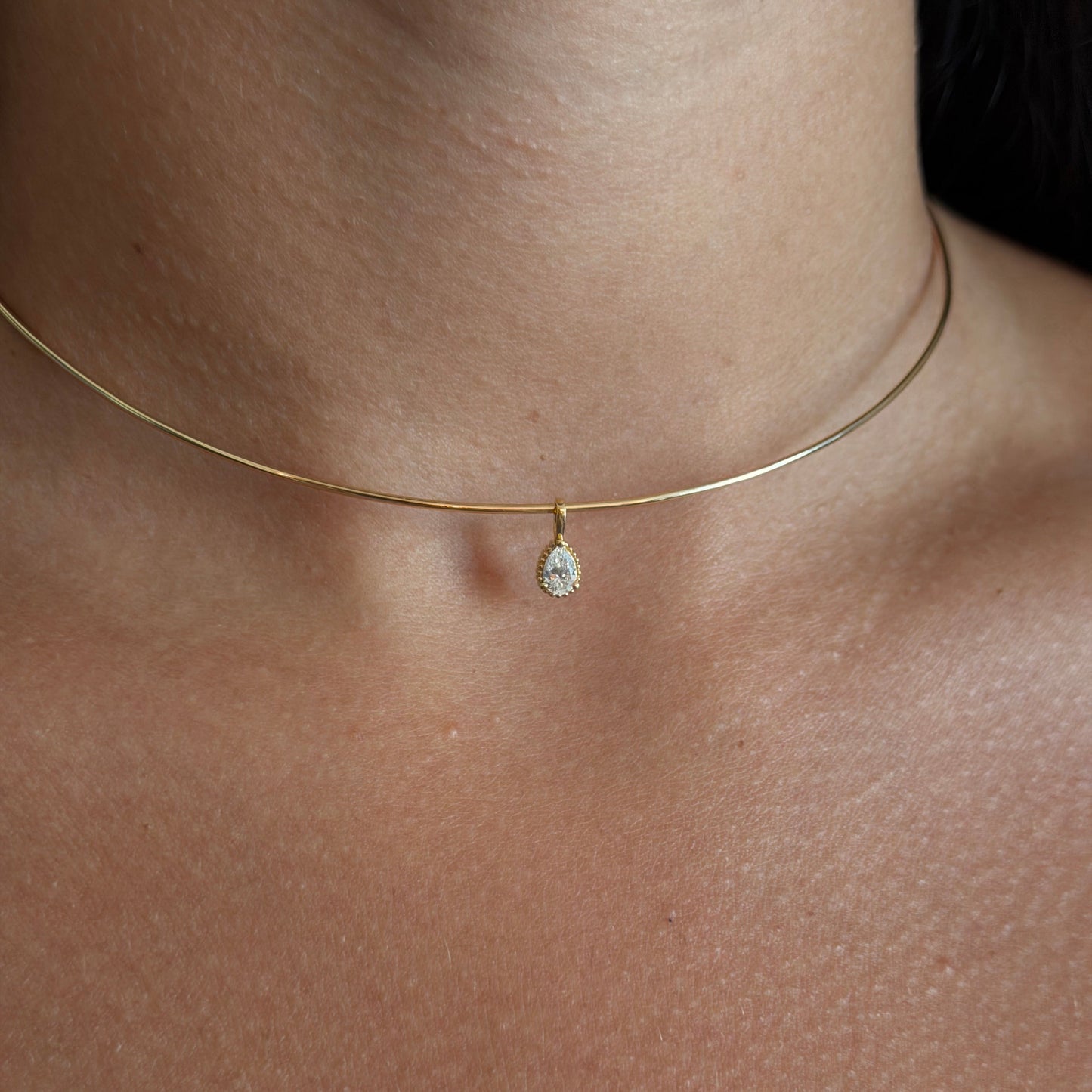 Gold necklace with a small pendant on a person's neck