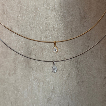 Two necklaces with teardrop-shaped pendants on a textured beige surface.