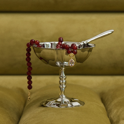 Silver bowl with berries and a spoon on a green cushion