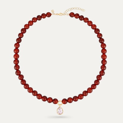 Red beaded necklace with a pink teardrop pendant on a white background
