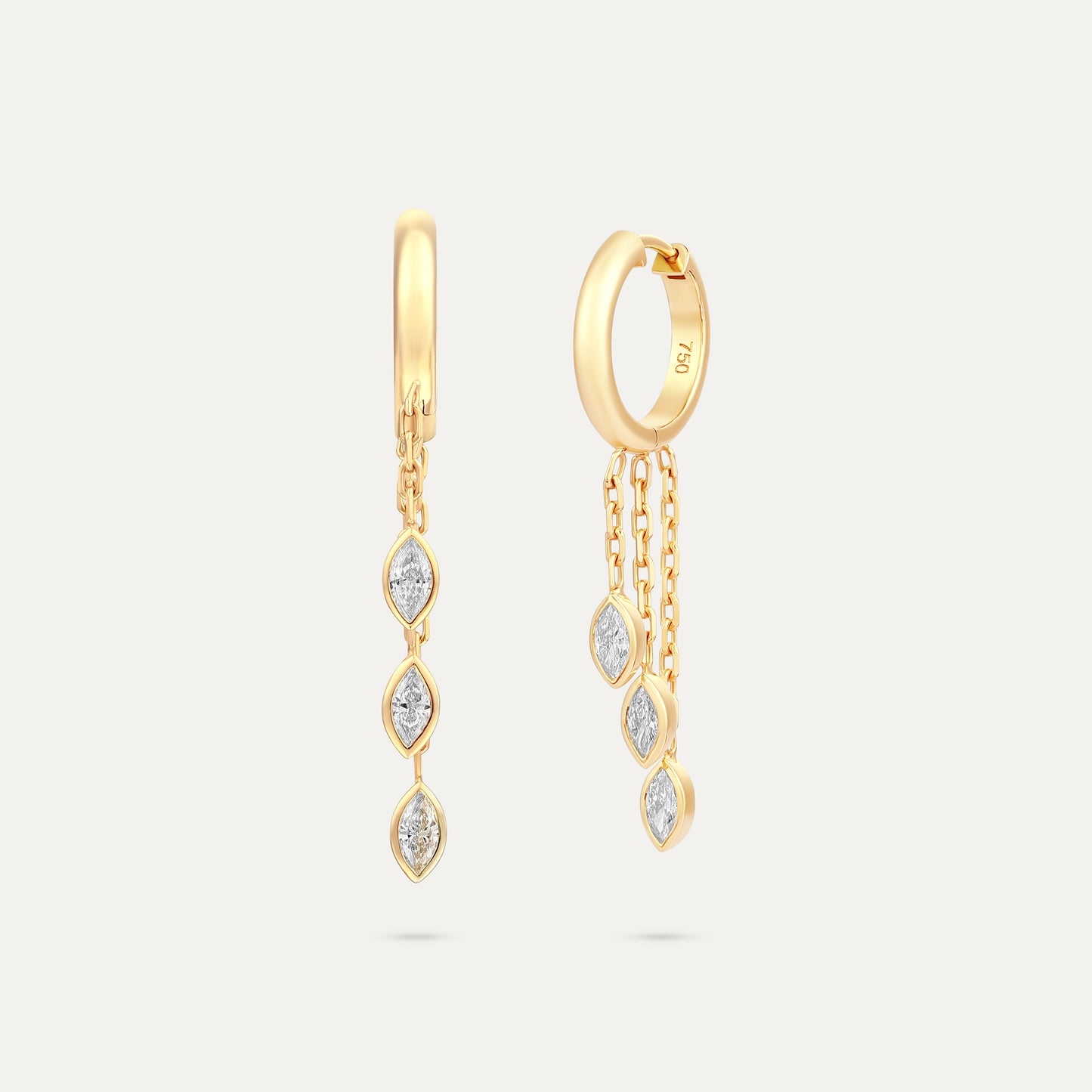 Gold hoop earrings with diamond-like stones on a light gray background
