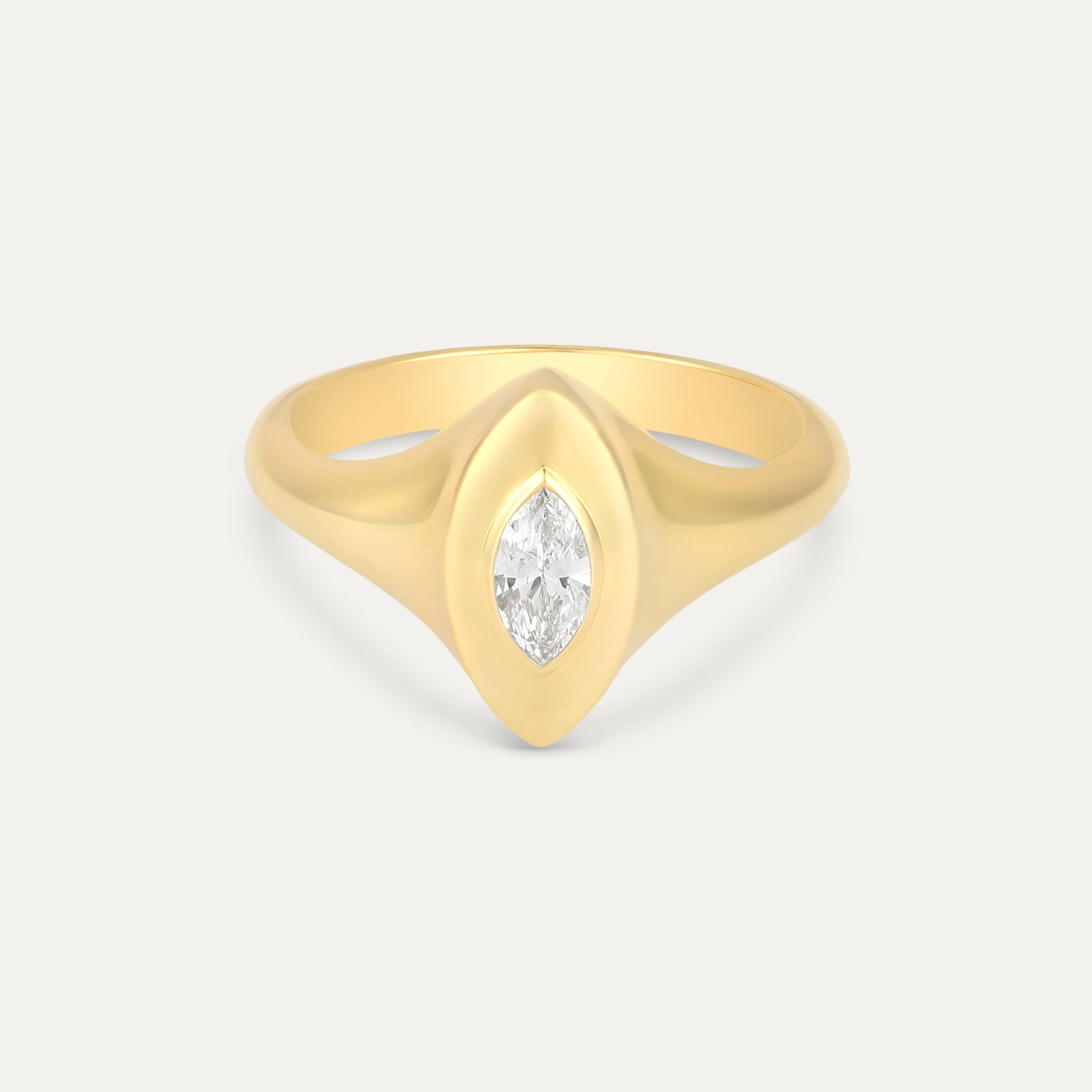Gold ring with a marquise-shaped diamond on a light gray background