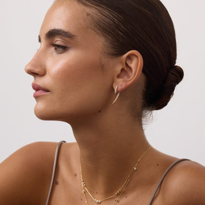 Woman wearing gold jewelry against a neutral background