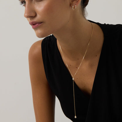 Woman wearing a gold necklace against a plain background