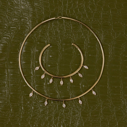 Gold hoop earrings with small dangling stones on a textured green surface