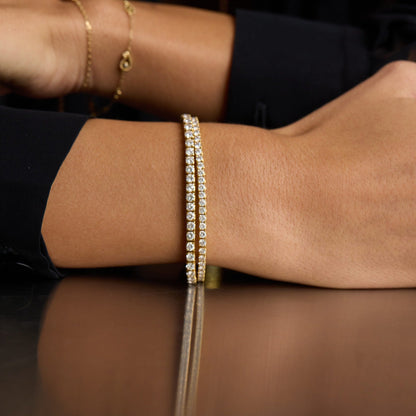 Close-up of a wrist wearing a gold bracelet with a reflective surface below