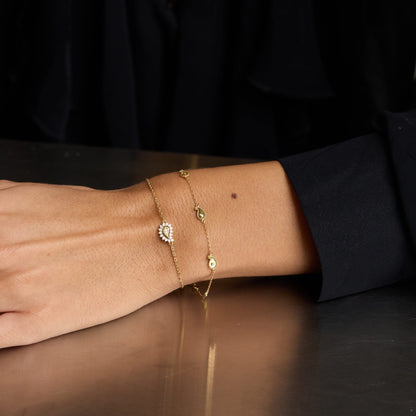 Close-up of a person's wrist wearing multiple gold bracelets on a dark surface