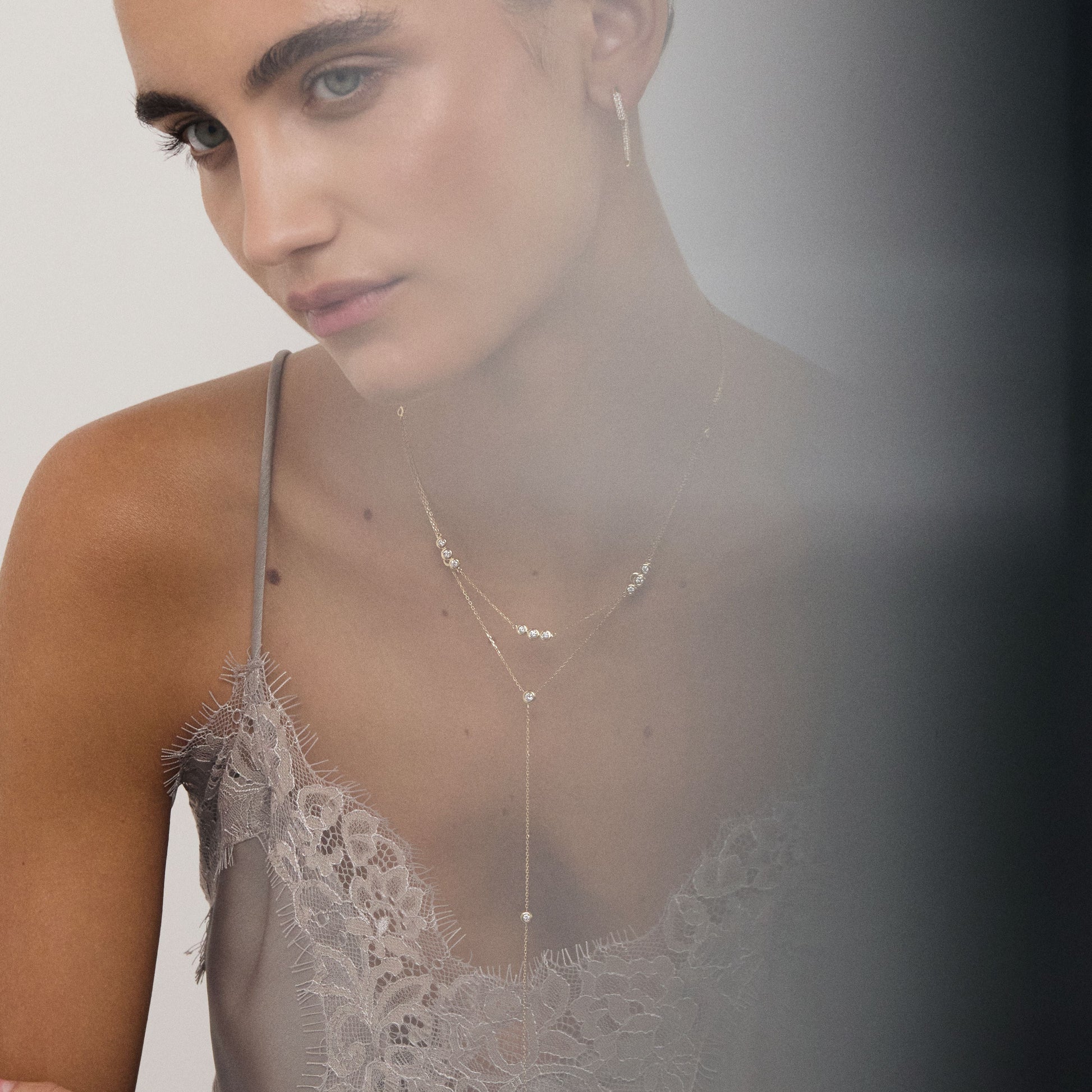 Woman wearing a delicate necklace with a plain background