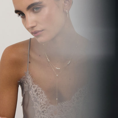 Woman wearing a delicate necklace with a plain background