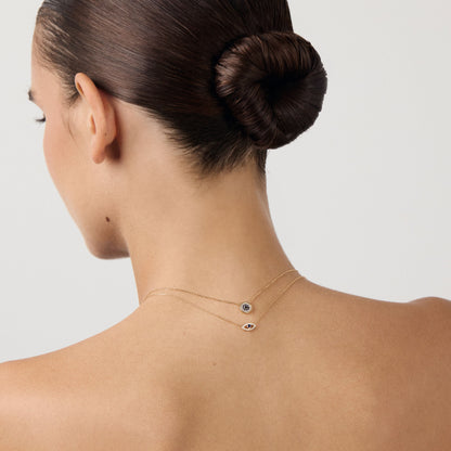 Woman with a stylish hair bun wearing a delicate necklace on a plain background
