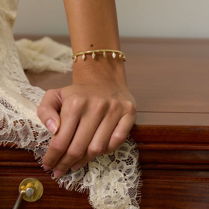 Hand with a gold bracelet on a wooden surface with lace fabric
