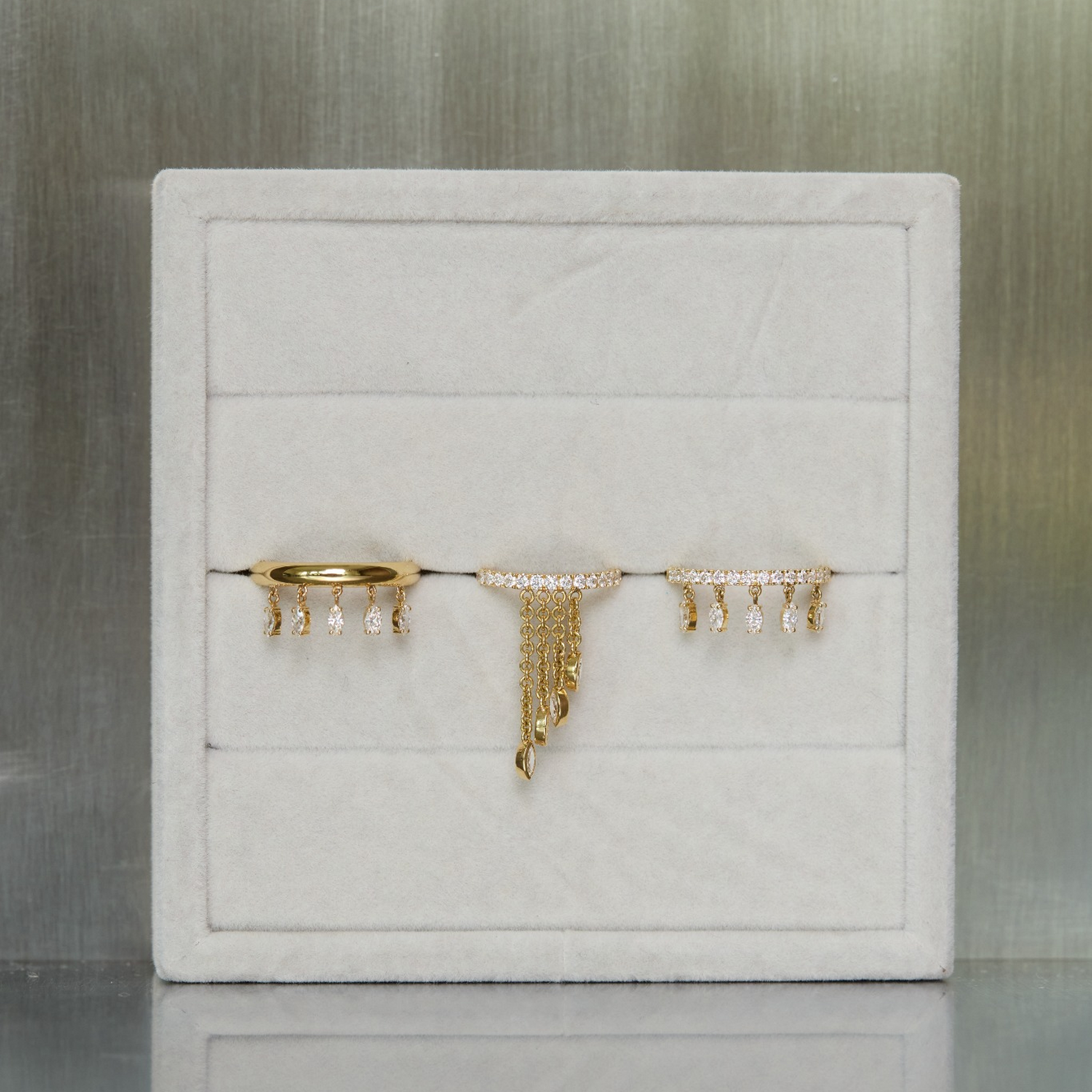 White jewelry box with gold and silver jewelry on a reflective surface